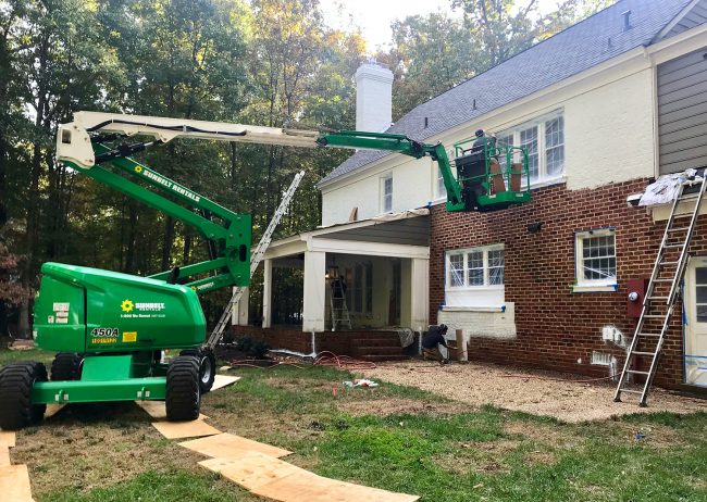 large crane lift used to paint the back of a brick house white