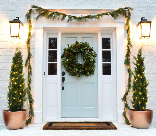 After Of Front Porch With Painted White Brick And Tranquility Blue Door With Christmas Holiday Decorations Garland Magnolia Wreath Faux Trees