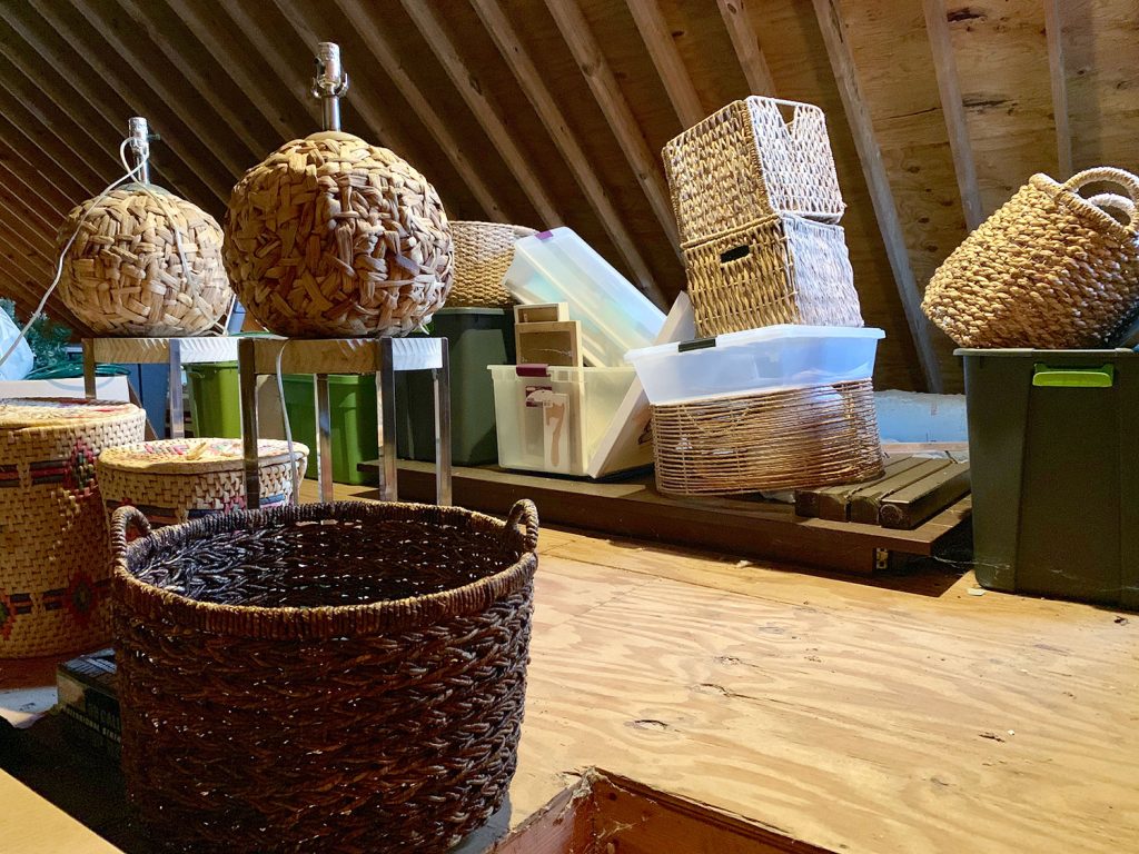 Unfinished attic filled with wicker baskets and tupperware bins