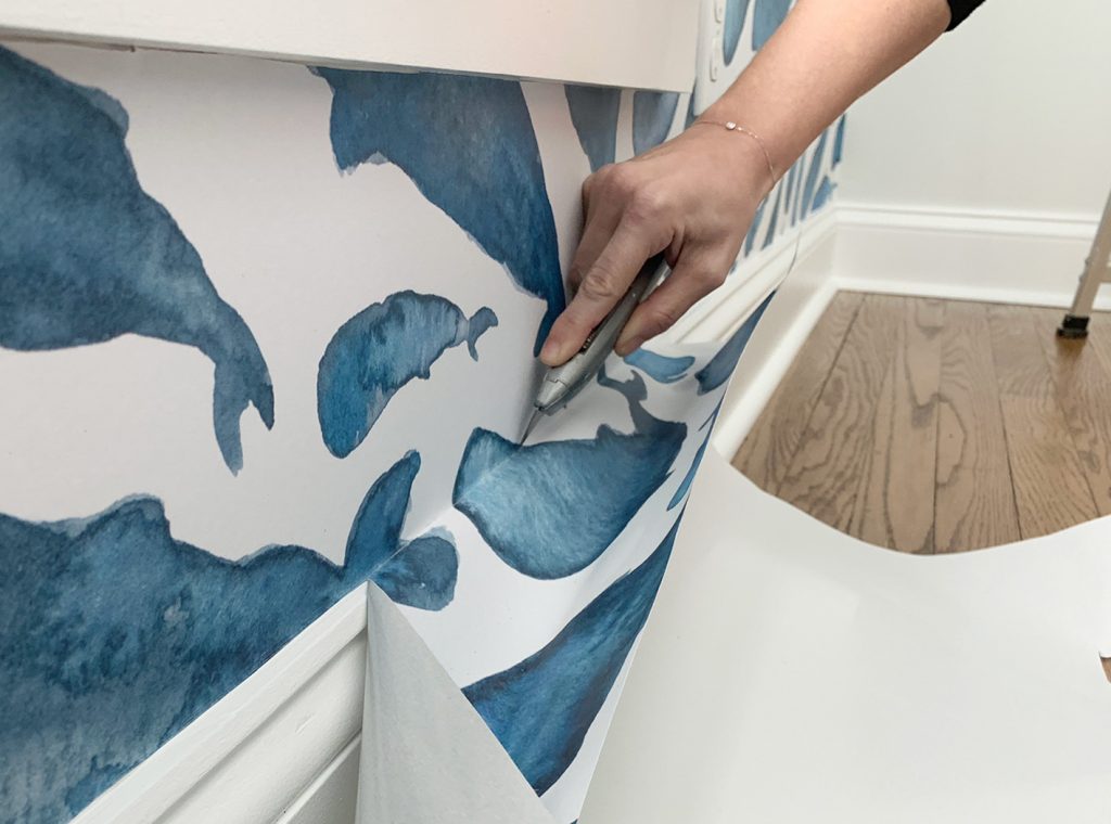 Cutting Off Excess Peel-And-Stick Wallpaper Along Baseboard