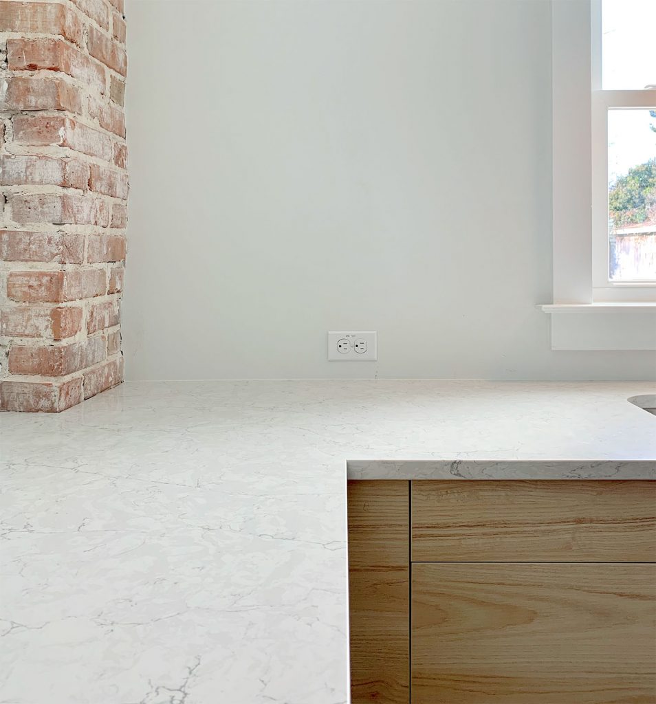 Silestone Pearl Jasmine Quartz counters with wood cabinets and brick chimney