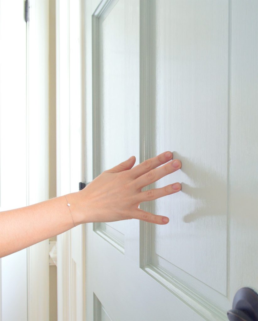 Close up of hand reflected in glossy finish of front door paint