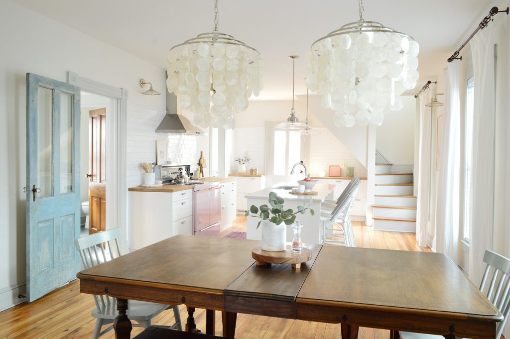 view into beach house kitchen through dining room capiz chandeliers