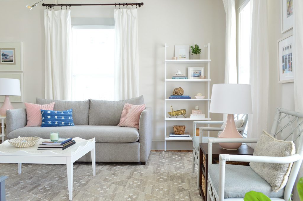 white heron walls in beach house living room with gray sofa and tall bookcase