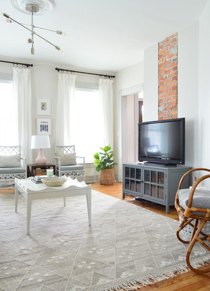 brick chinmey with TV on dark gray media cabinet with neutral furnishings