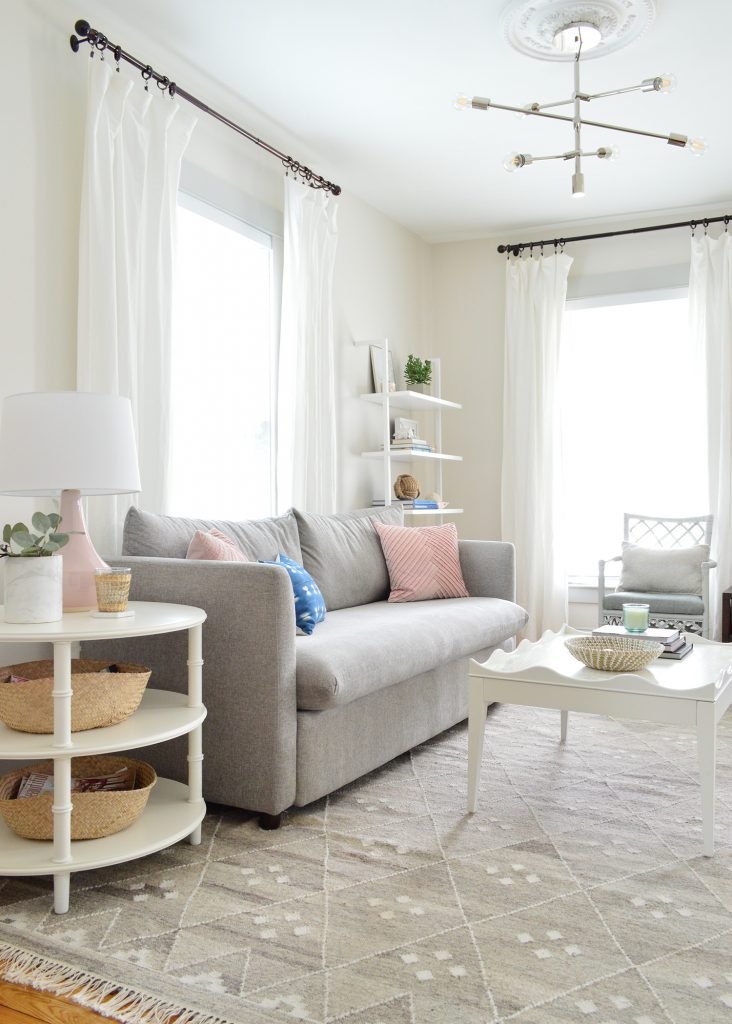 bright neutral living room gray sofa with round side table and scalloped coffee table