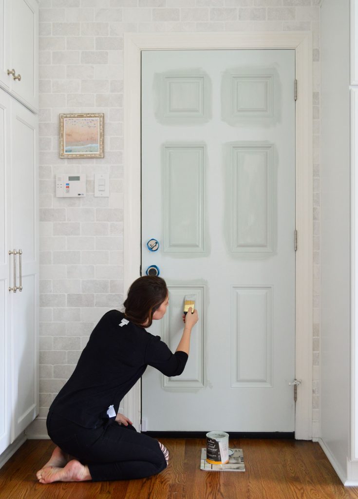 Sherry aplicando tinta de alto brilho na porta da cozinha com pincel de ângulo curto