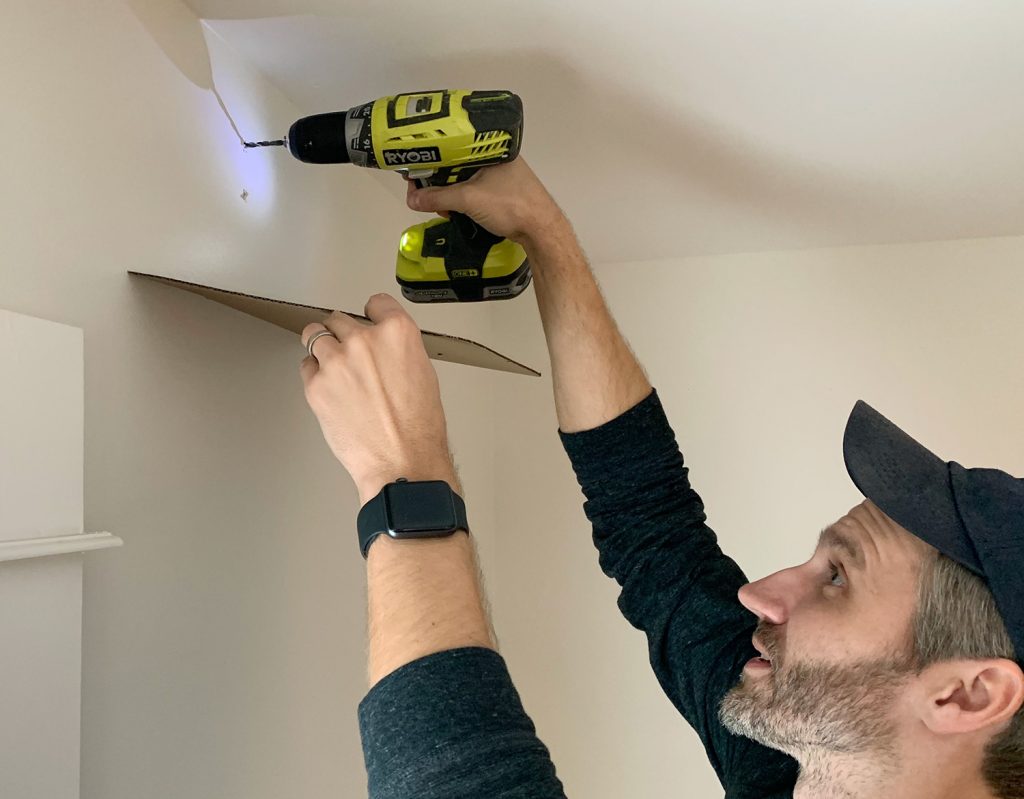 Drilling larger holes for curtain rod using cardboard to catch dust