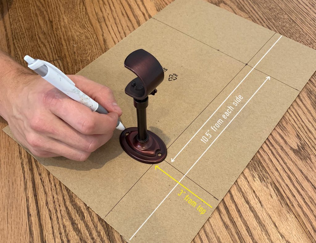 Marking lines on cardboard to make a curtain rod hanging template