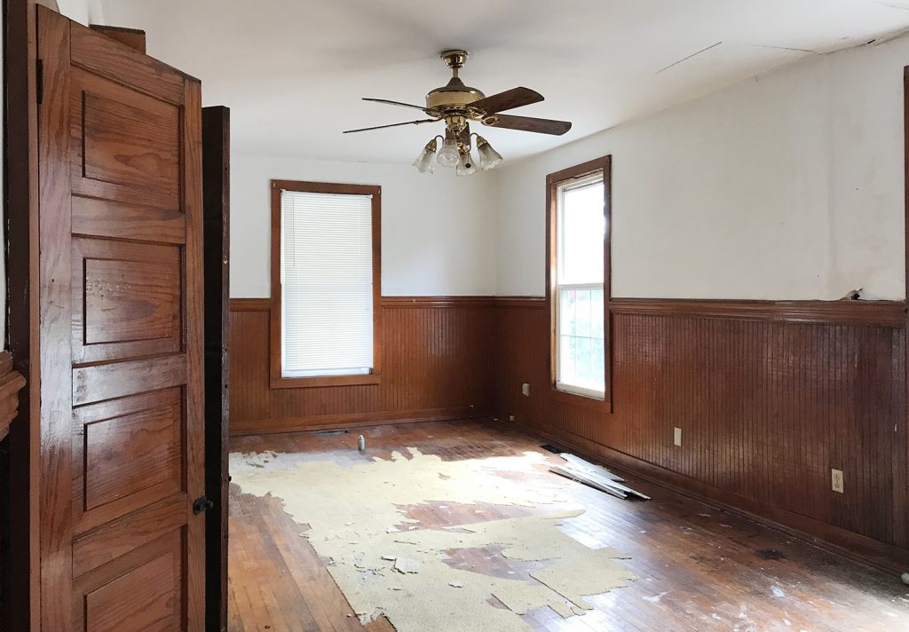 Before Angle of Living And Dining Room With Dark Wood Paneling