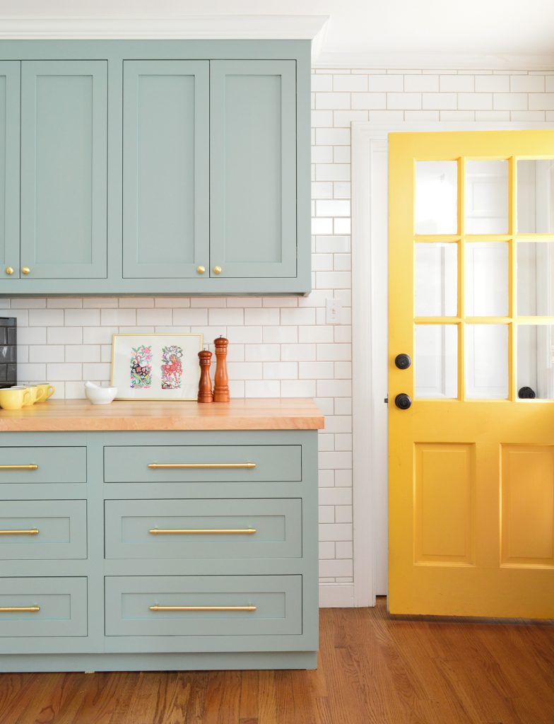 Porta dos fundos em amarelo abelha contra armários de cozinha em azul verde Halcyon