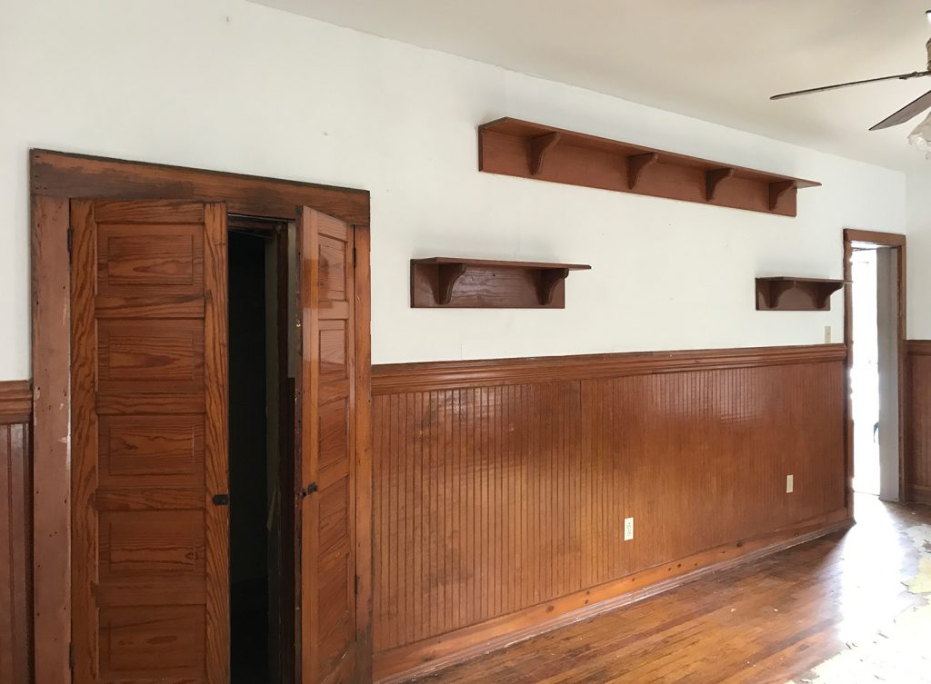 Before Angle Of Living Room With Dark Wood Paneling And Shelves