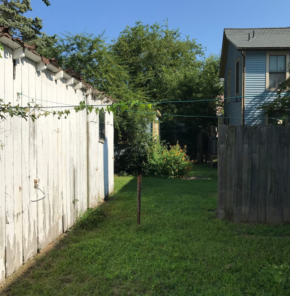 Before Photo Of Duplex Backyard With Old Fence and Shed
