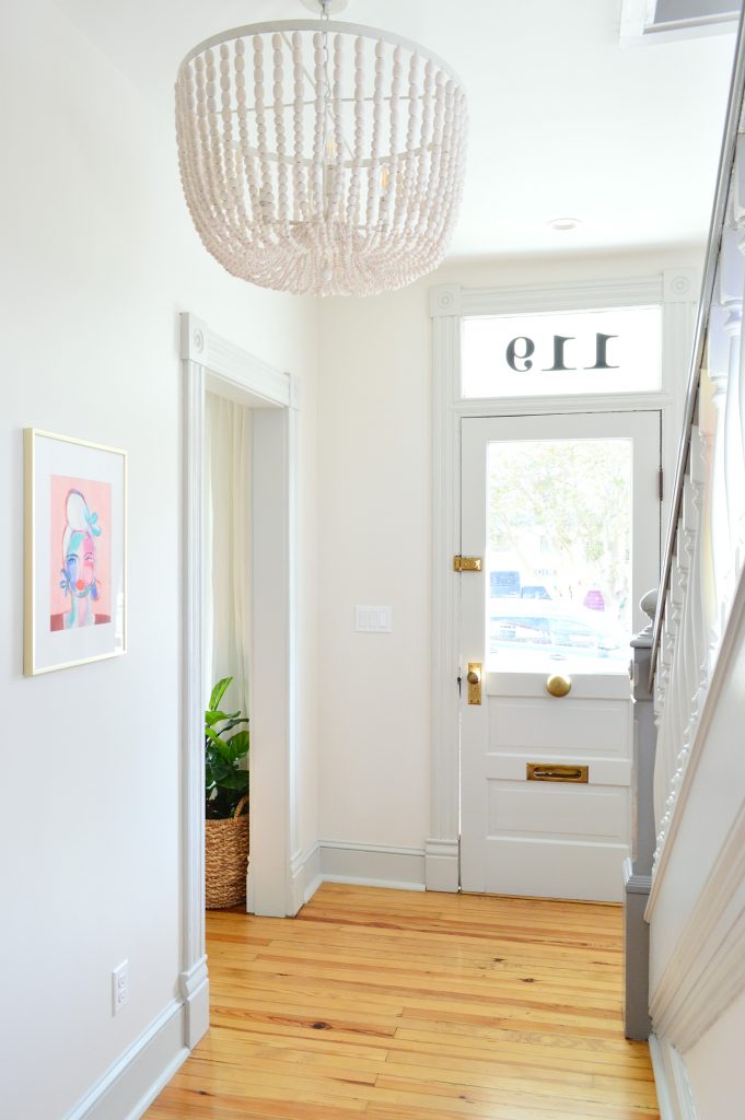 Beaded Chandelier In Beach House Foyer With Glass Front Door And Pink Art