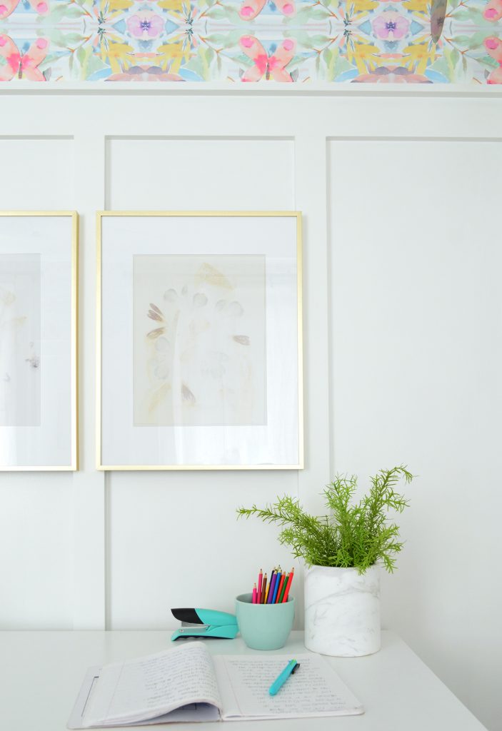 Desk With Gold Frames Hung On Board And Batten