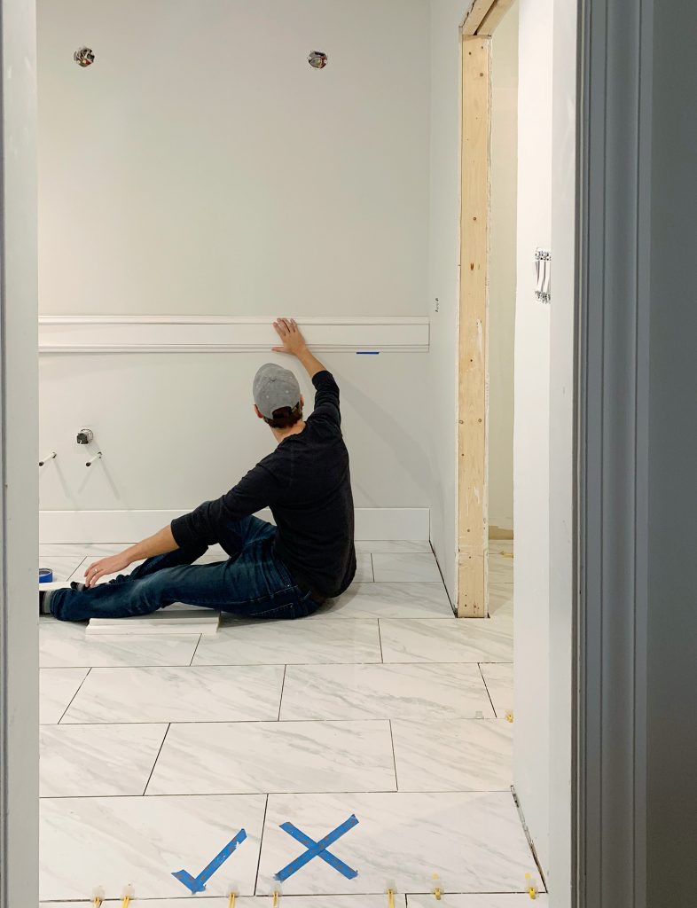 John Holding Test Piece Of Wall Molding In Bathroom