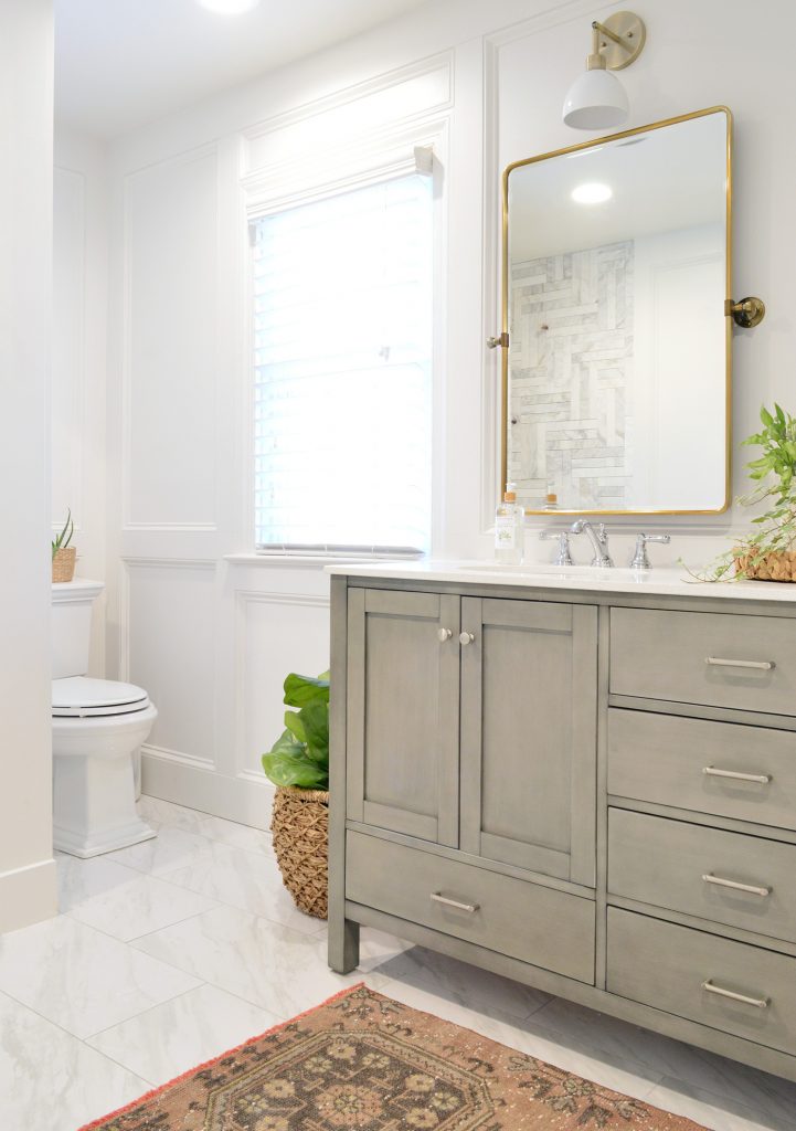Bathroom Makeover With Gray Vanity Installed With Brass Mirror And Decorative Wall Molding