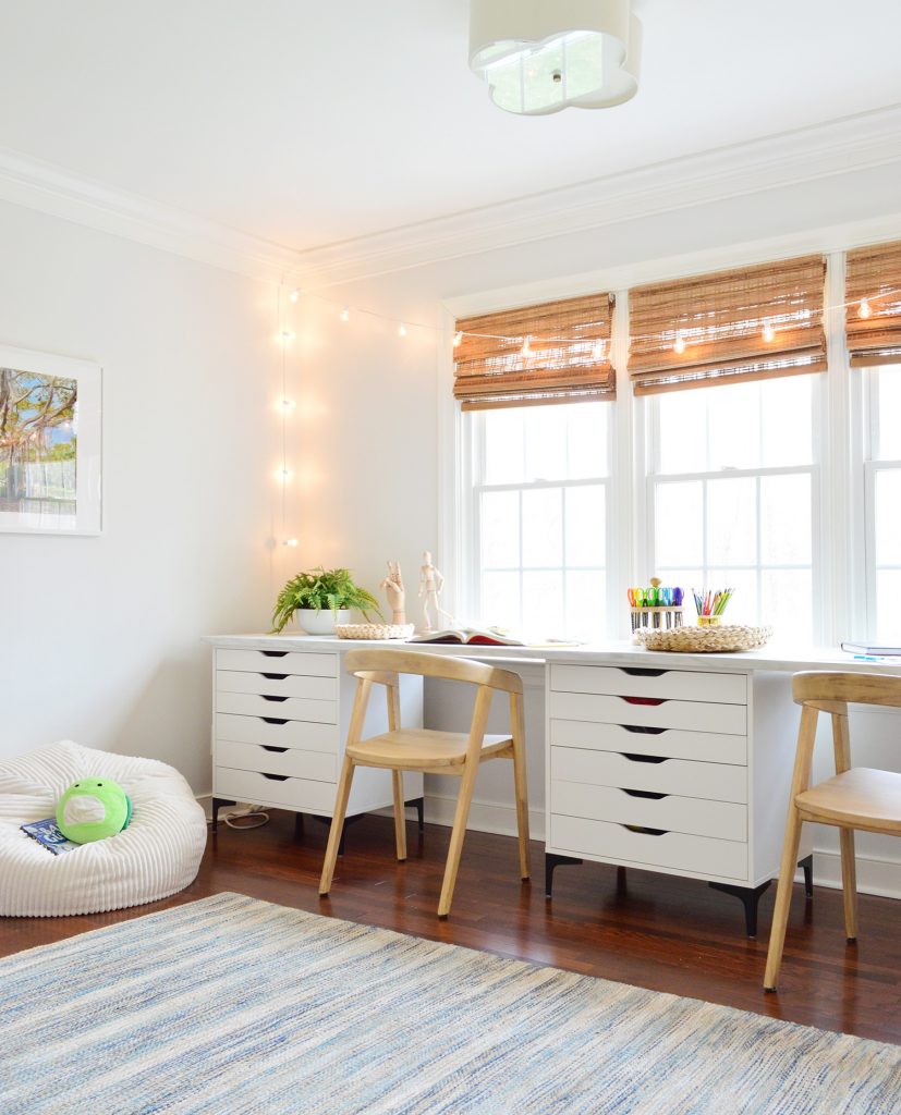 Kids Art Room With Two Wood Chairs Along Long Art Desk Workspace With String Lights