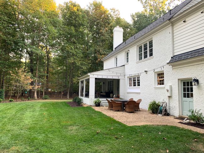 After Of Backyard With Painted Brick Colonial Home And Large Grassy Yard