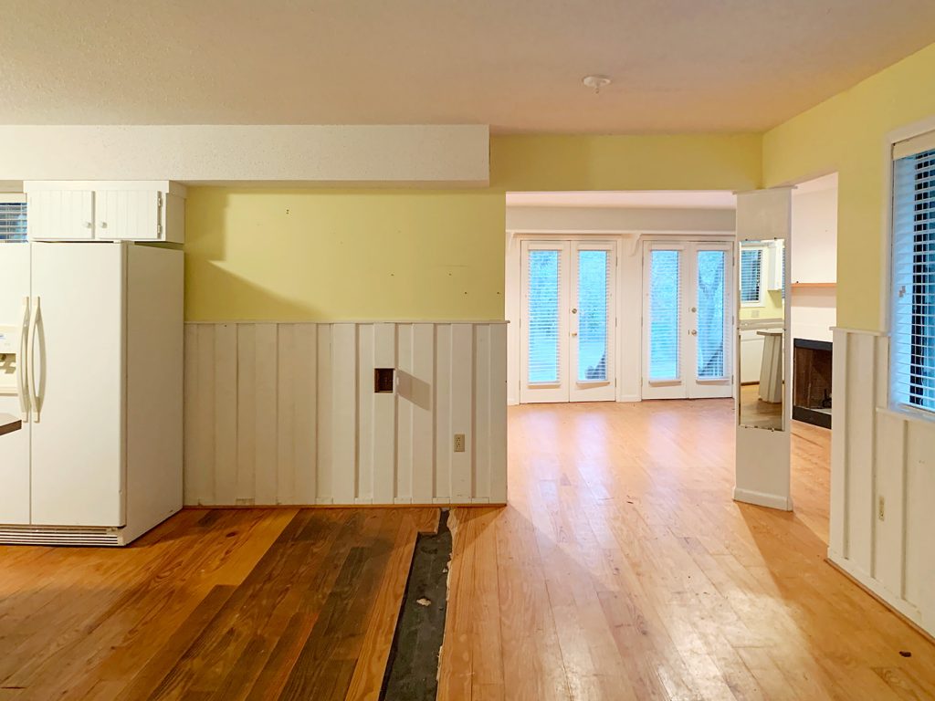 Before photo of seating area in kitchen with wide opening into living room area