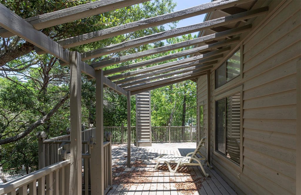 Before photo of upstairs deck with brown paint chimney and pergola