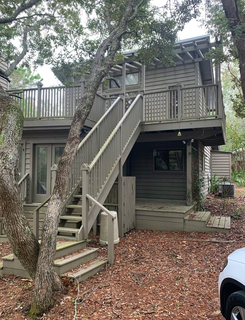 Before photo of side of house painted brown and with stairs