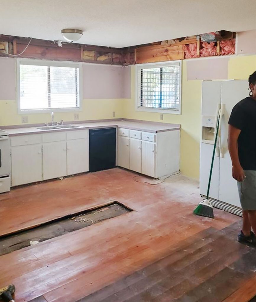 Photo of kitchen renovation mid demolition with mauve wall paint behind cabinets