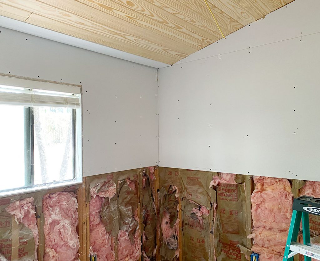 Boys bedroom during renovation with vaulted planked ceiling and drywall removed