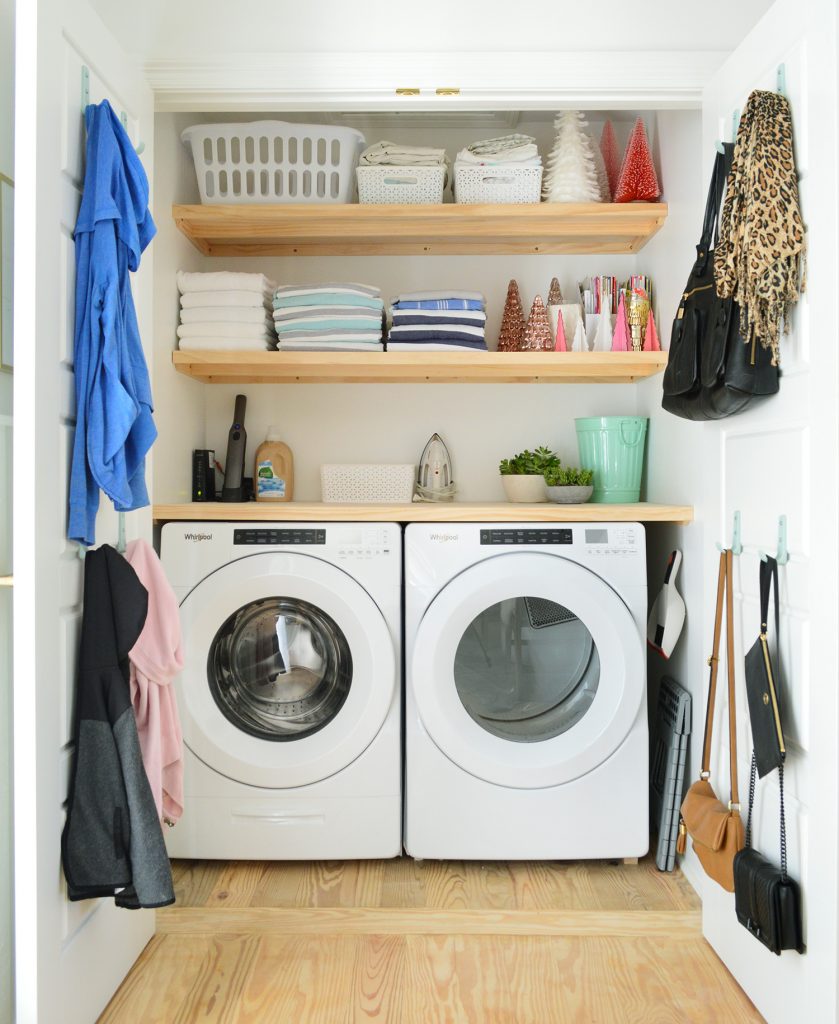 Front loading laundry appliances in closet with wood shelves on top