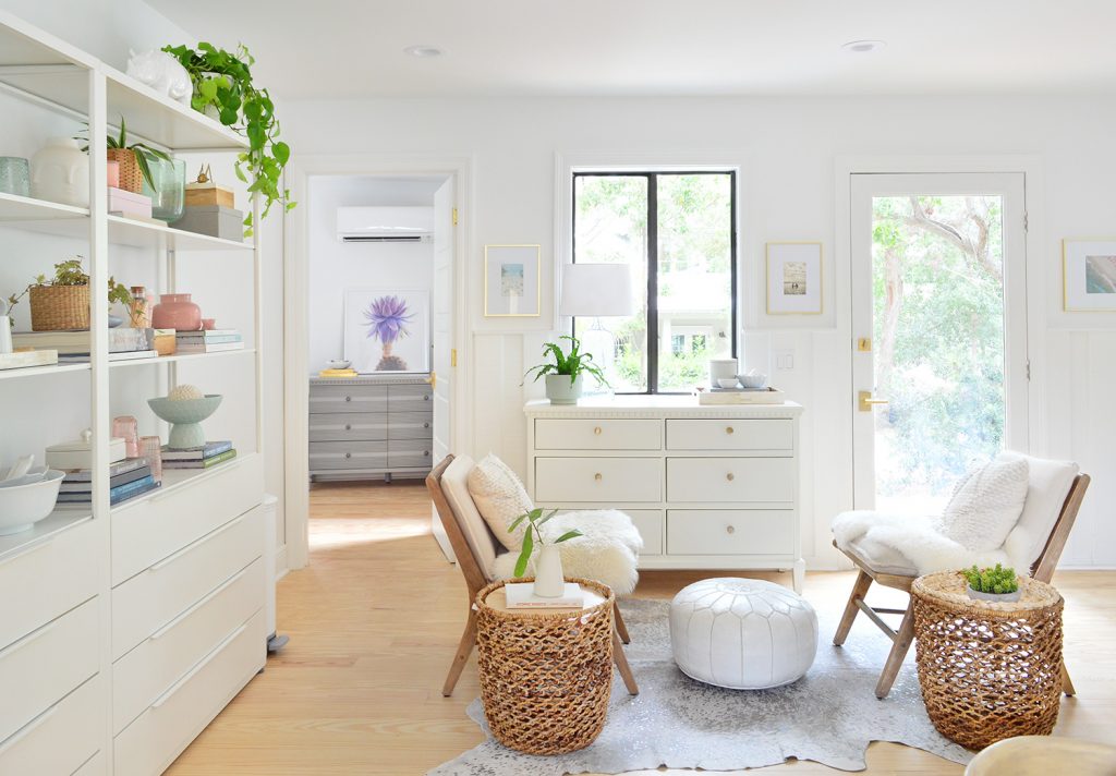 Beachy sitting room with white shelves and large dressers with floating chairs and baskets