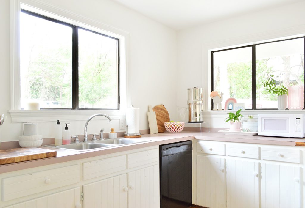 Black Dishwasher Among White Cabinets In Minimal Beachy Kitchen