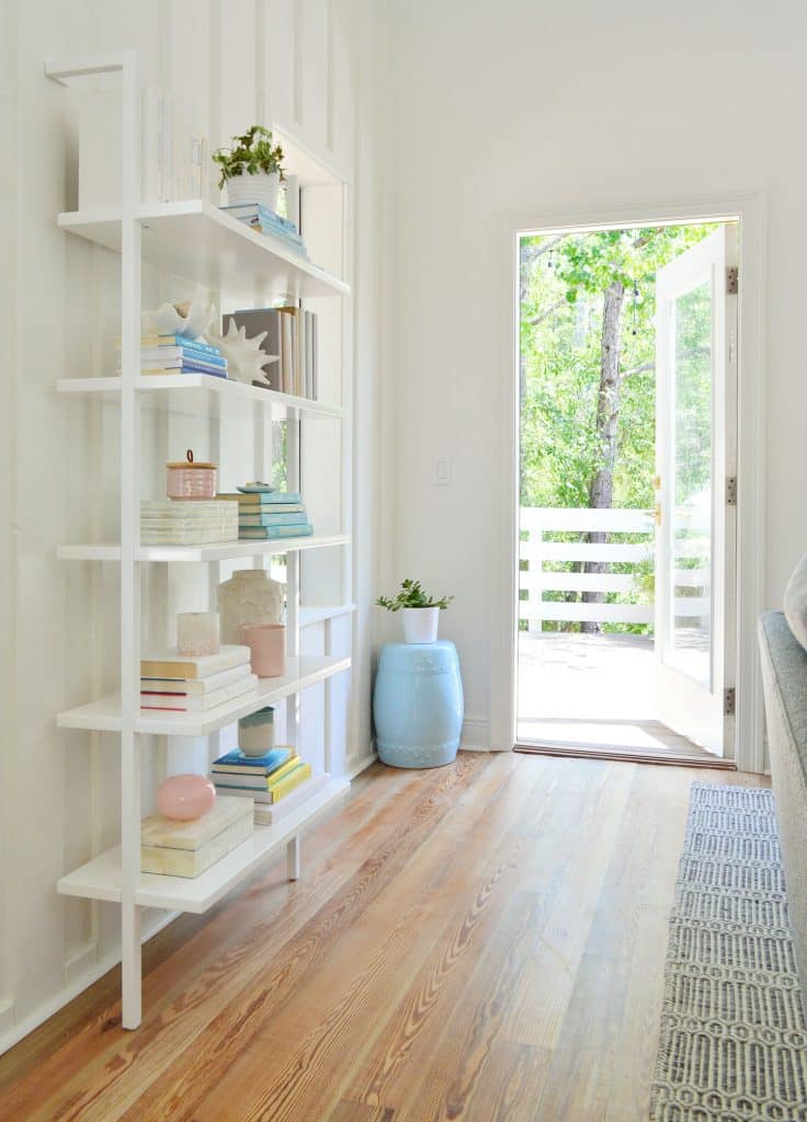 Floating White Bookcase With Door Open To Deck