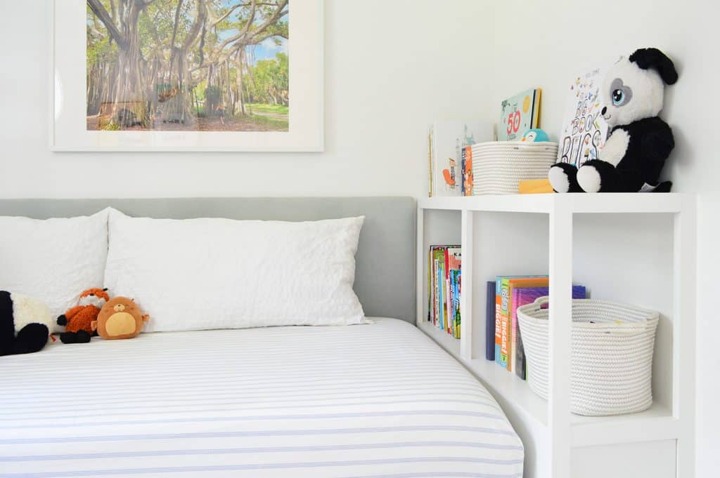 After photo of built-in bookcase at foot of bed with books and stuffed animals