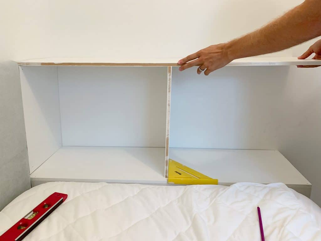 Fitting top shelf of built-in bookcase at the foot of boys bed