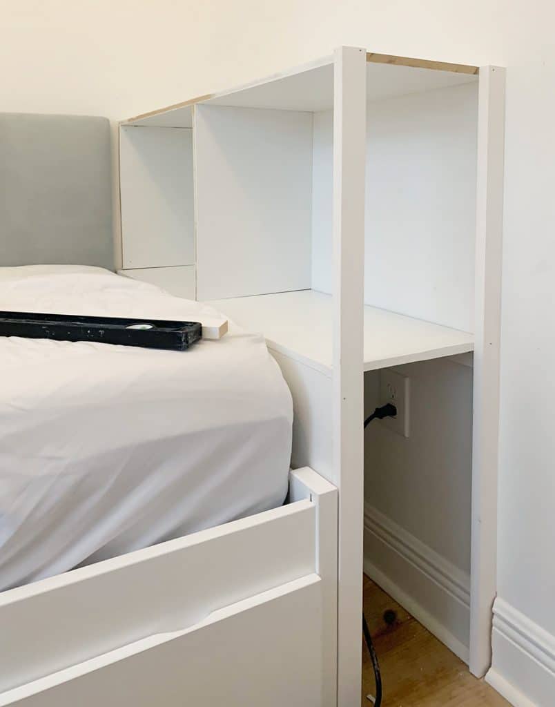 Side posts attached to built-in bookcase in boys bedroom with open shelf facing door