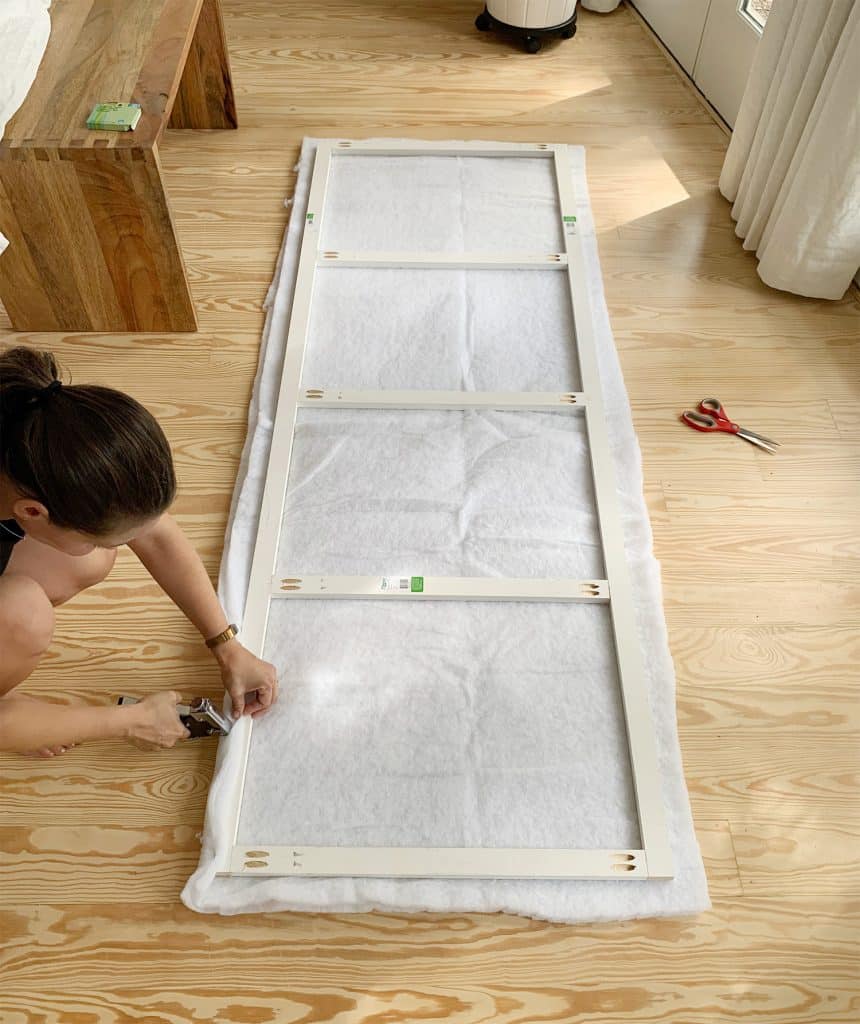 Sherry stapling two layers of batting to second larger wood frame for DIY headboard