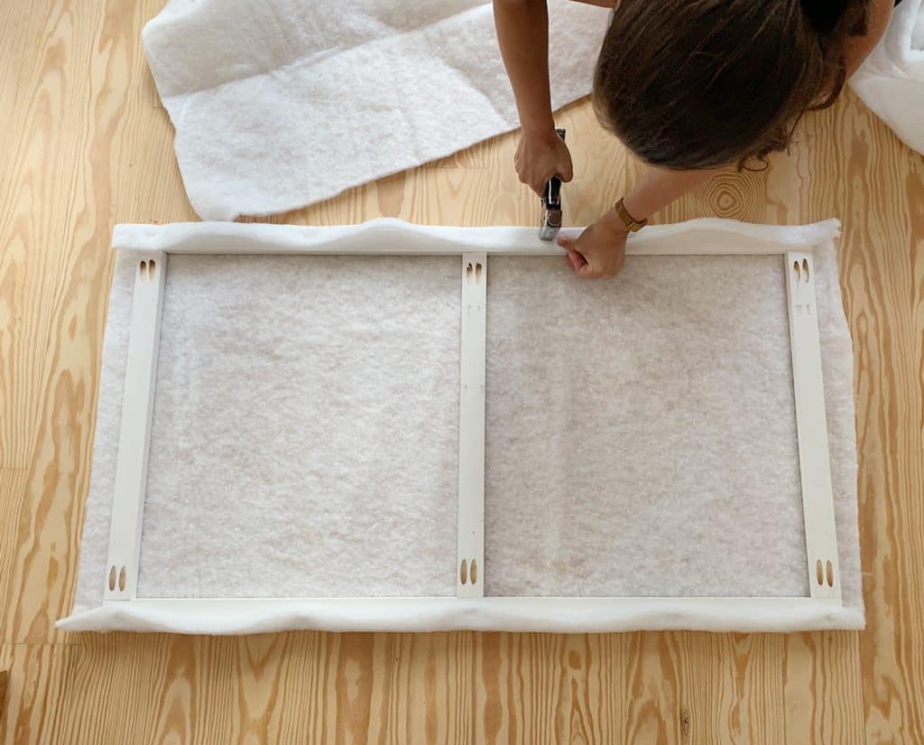 Sherry stapling fabric batting around wood frame for DIY upholstered headboard