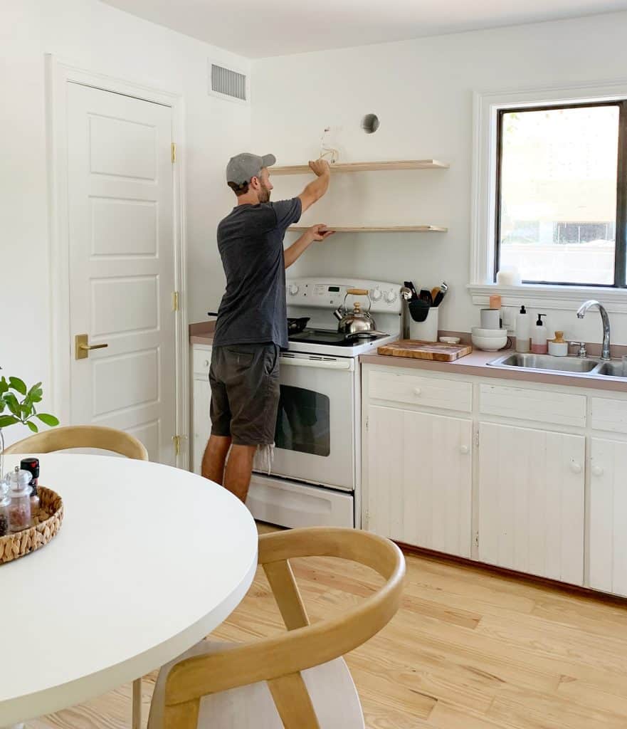 John Holding Up Plywood Piece To Mock Up Wood Shelf Placement