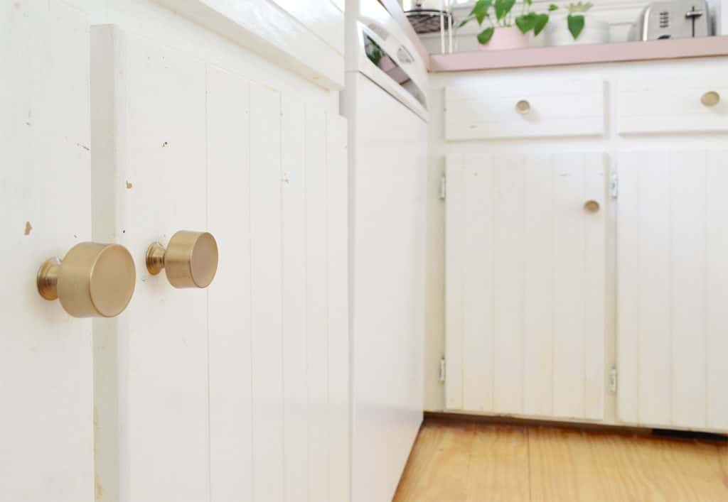 Close up before photo of white cabinets with paint flecks near knobs