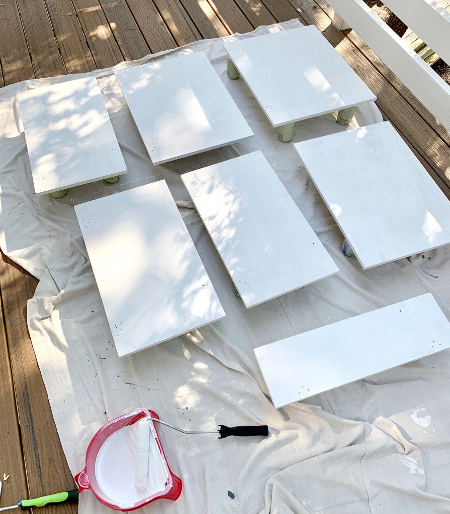 Cabinet doors laid on drop cloth with coat of white primer drying