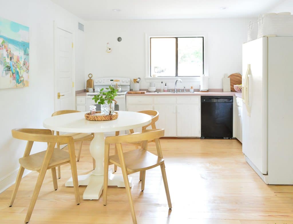 Kitchen with white cabinets black dishwasher and off center round table