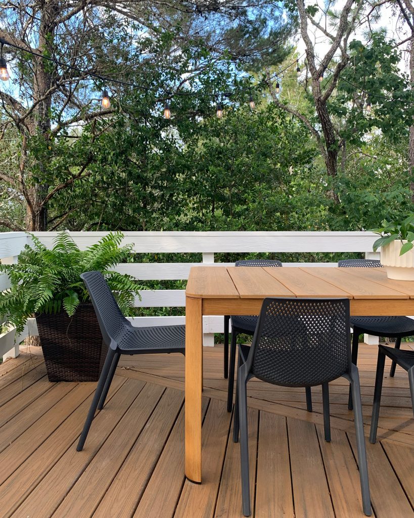 Close Up View Of Metal Faux Wood Table With Black Plastic Chairs