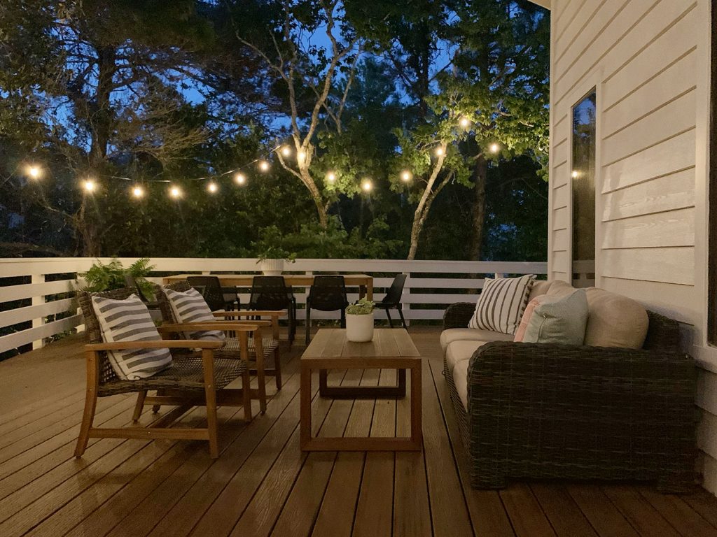 Vista noturna da área de estar do deck externo com luzes de corda