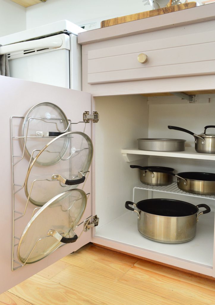 Pots and pans organized in small kitchen with lid mounted on cabinet door