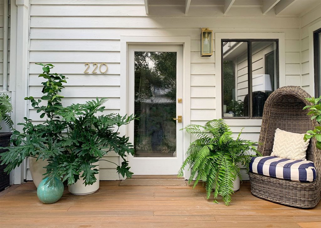 Varanda frontal com porta de vidro e muitas plantas