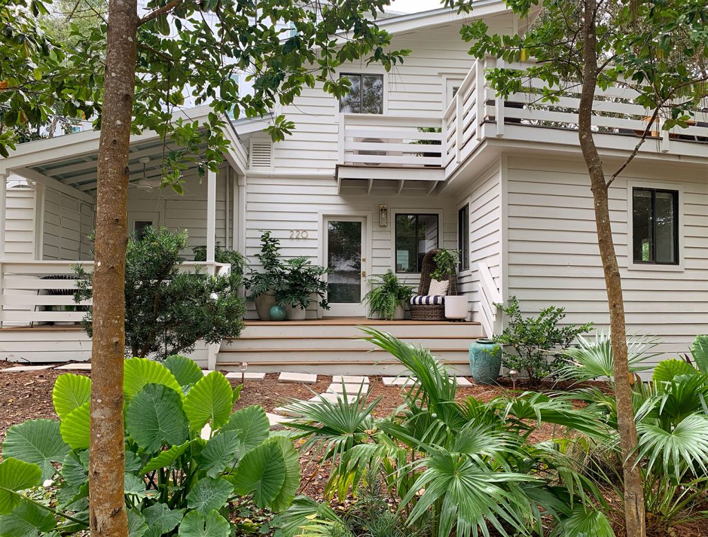 Casa com revestimento branco e plantações tropicais