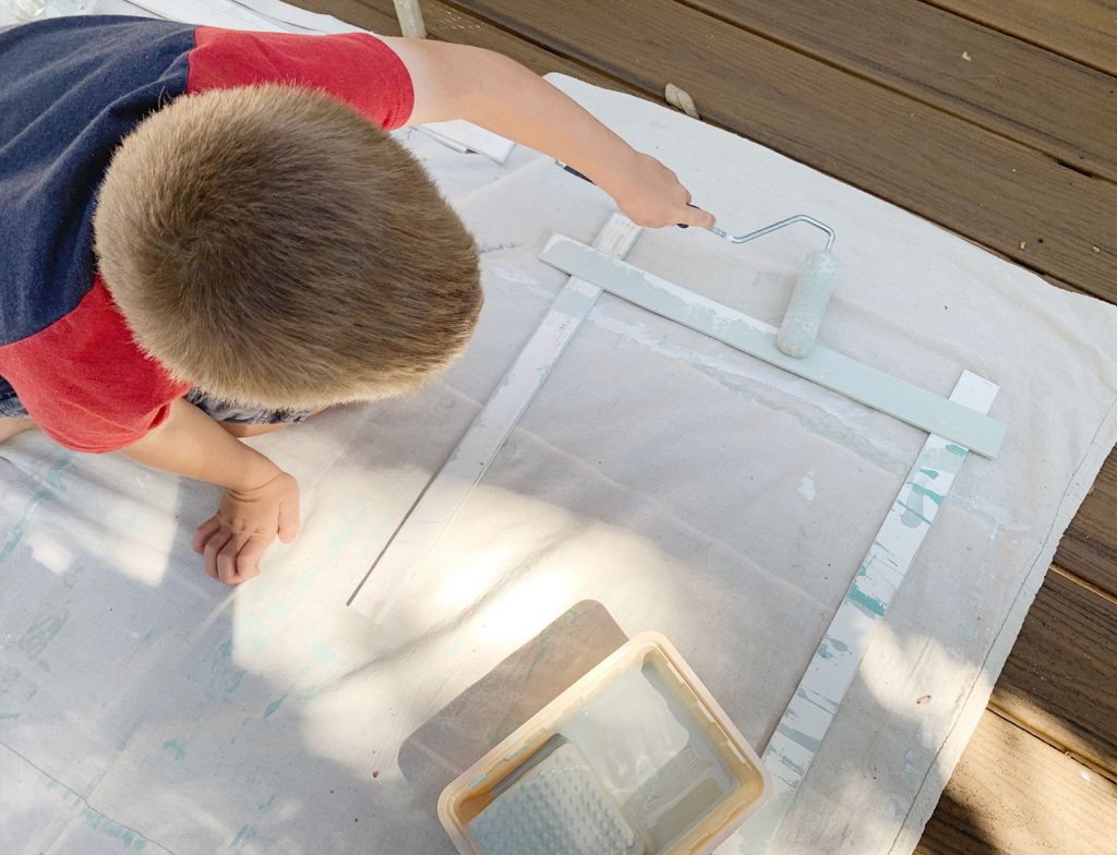 Young Boy Painting Wood Piece With Small Foam Roller