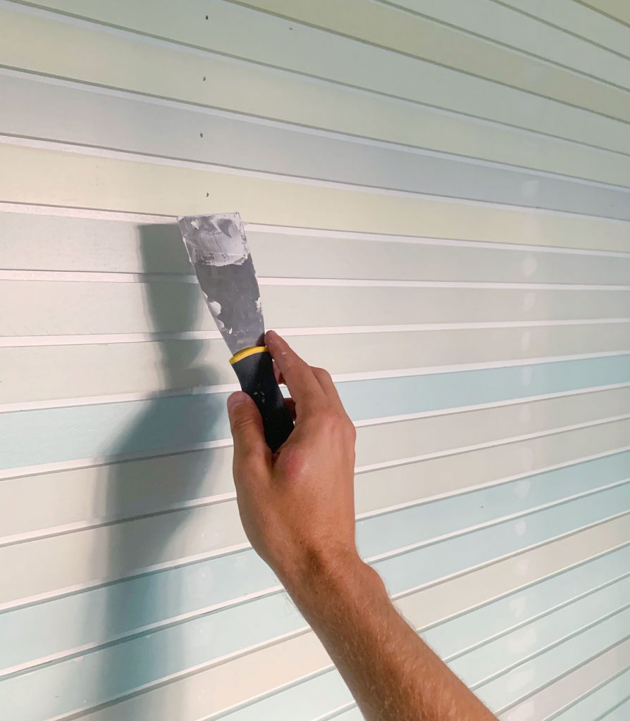 Hand Spackling Nail Holes On Striped Wall Treatment