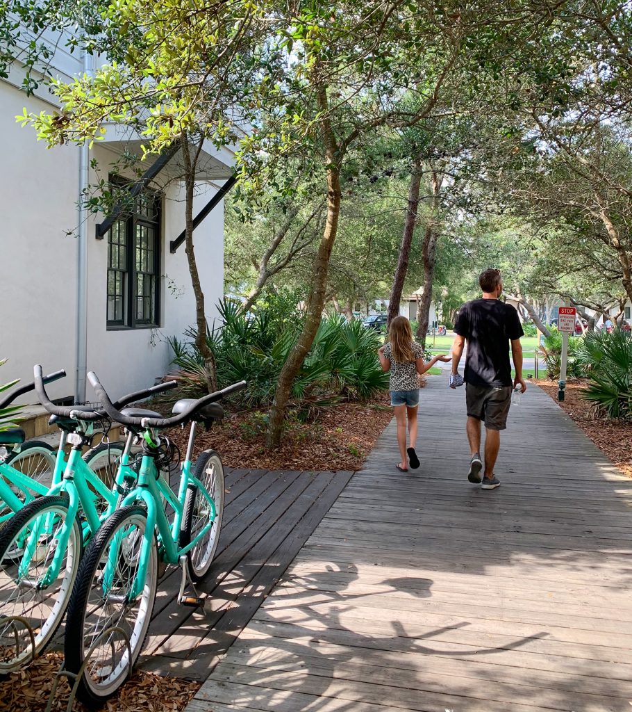 John Walking With Daughter Through Beachy Neighborhood Covered With Trees