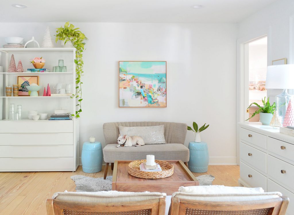 Seating area with settee against wall with painting above next to white metal shelf